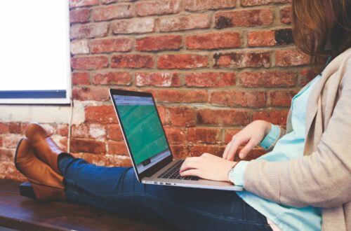 Woman Working On Laptop Against Brick Wall Free Stock Picture