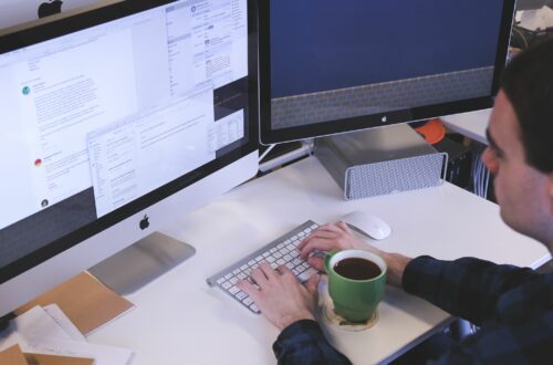 Man Working On Multiple Computer Monitors With Coffee Free Stock Picture