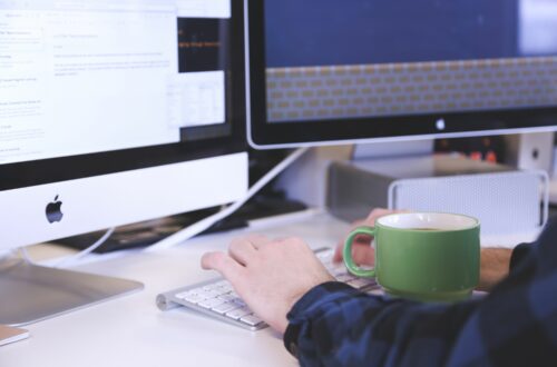 Person Working On Multiple Computer Monitors With Coffee Free Stock Picture